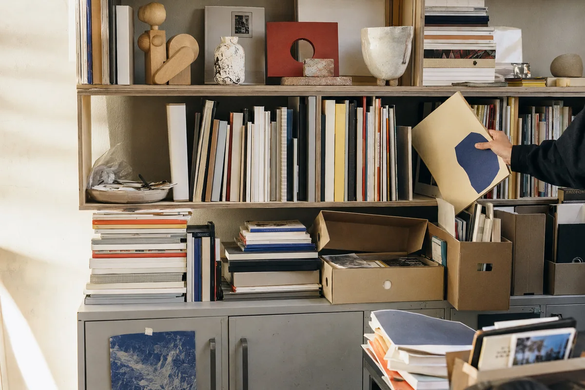A collected shelf of books, catalogues, stationery and design objects.